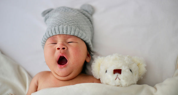 Newborn yawning and wearing a hat. Credit: Unsplash  Minnie Zhou.